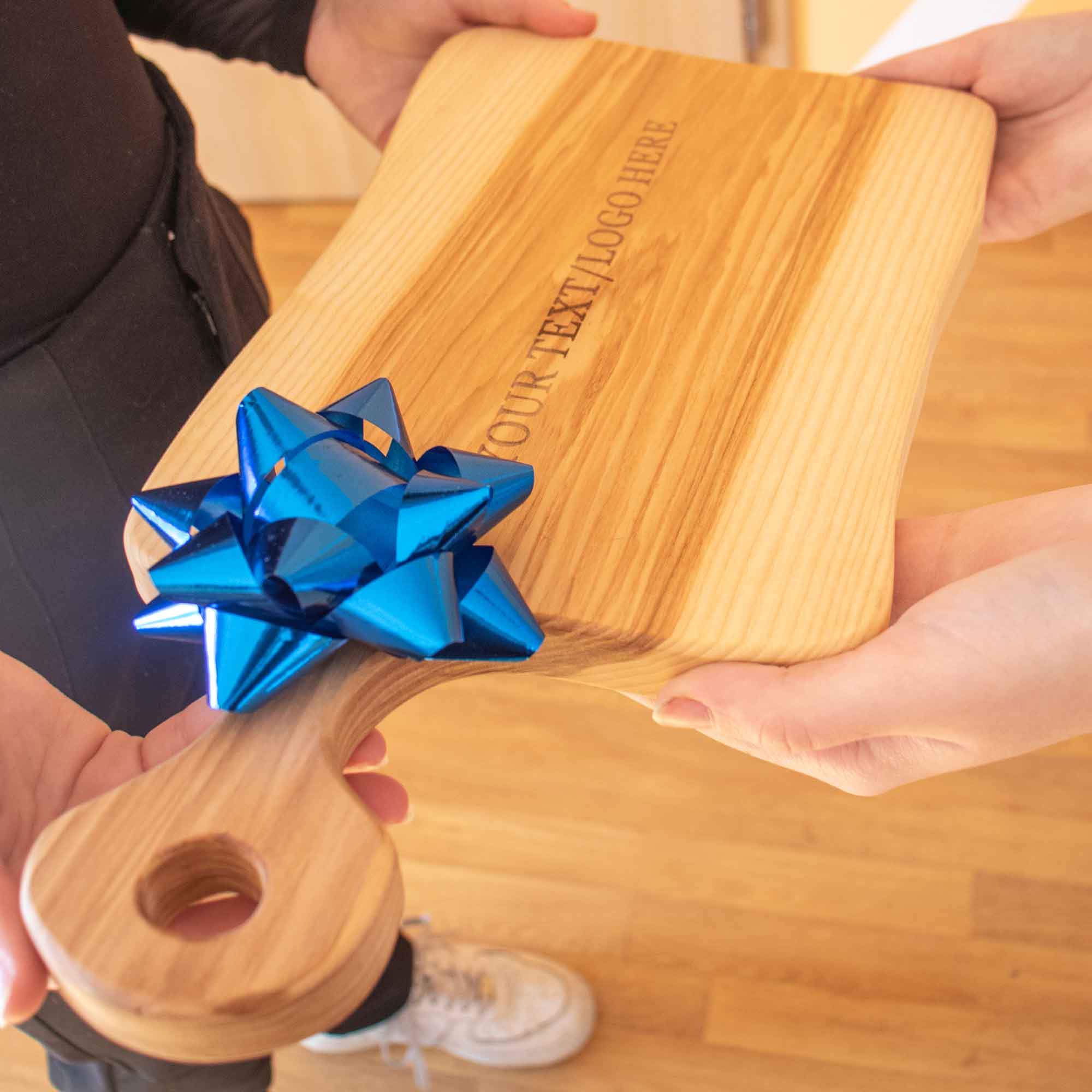 Personalized wooden cutting board held as a thoughtful teacher gift