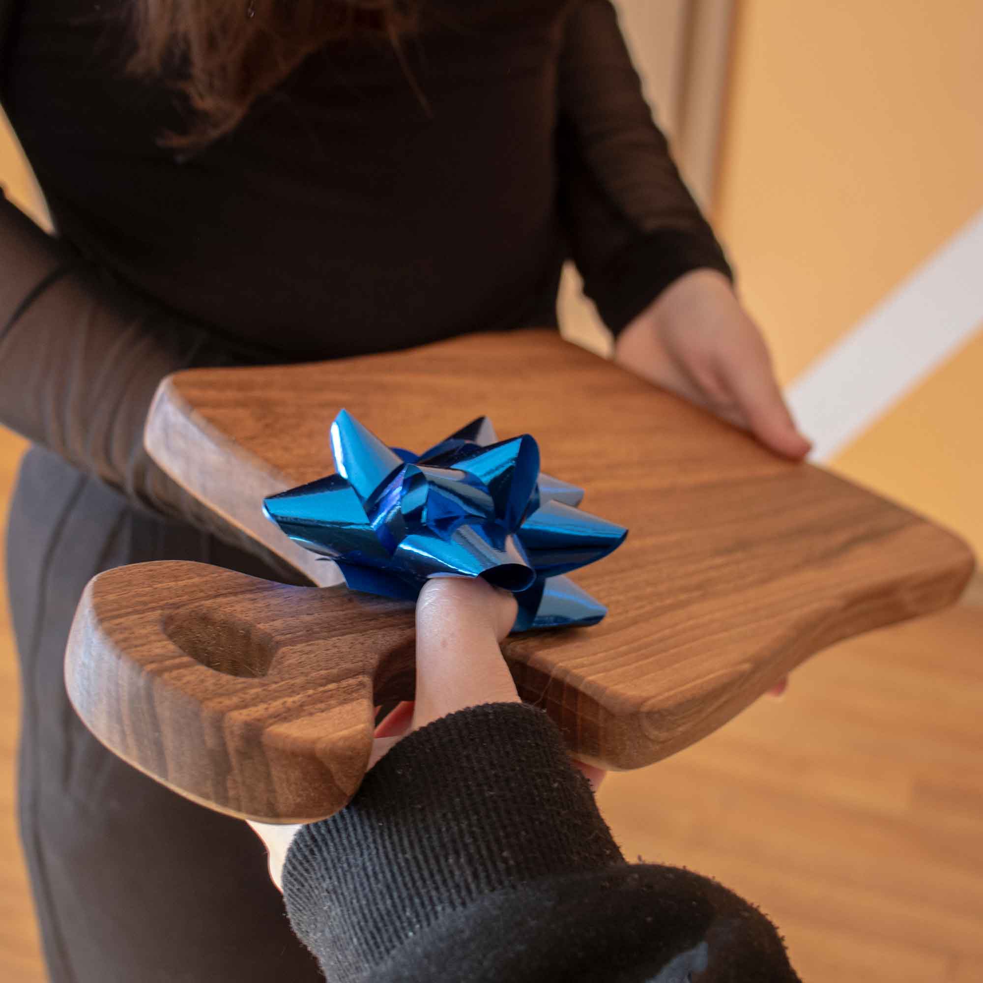 Personalized wooden board with a blue bow shown as a thoughtful wooden gift