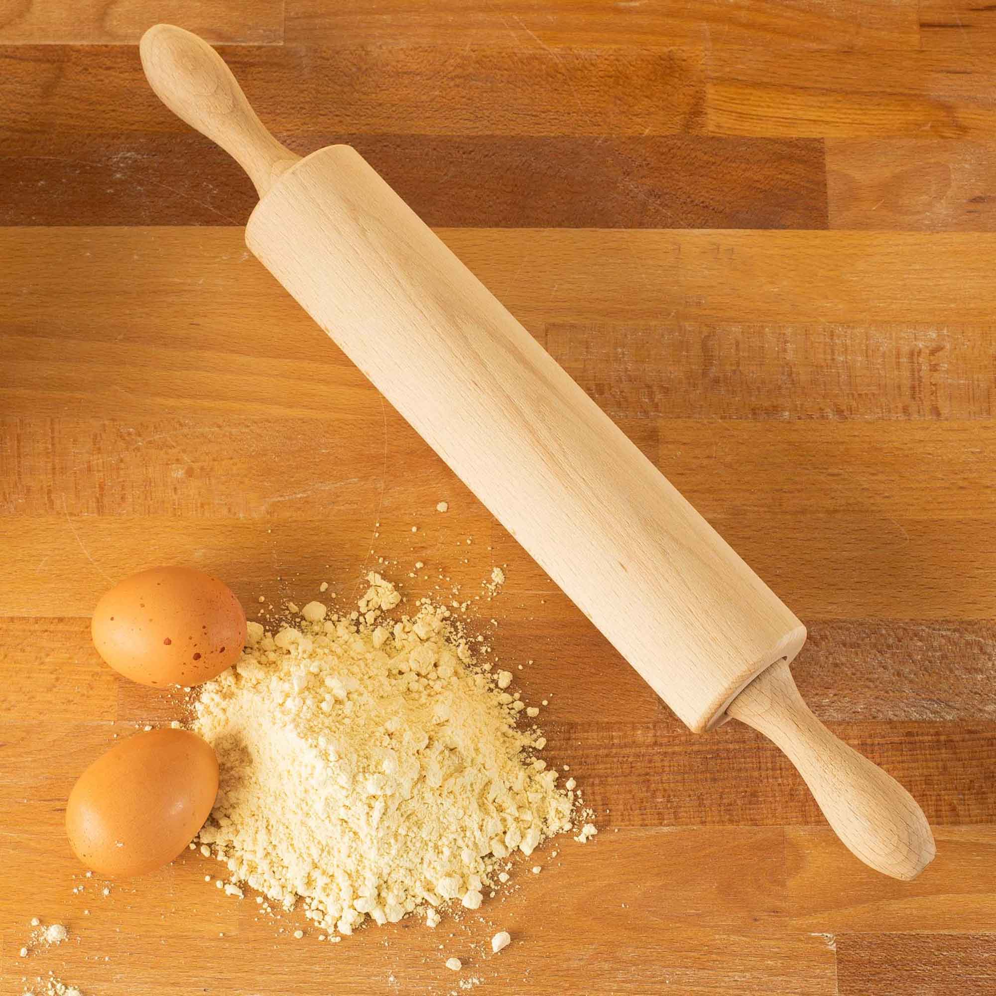 Wooden cutting board and rolling pin shown with baking ingredients