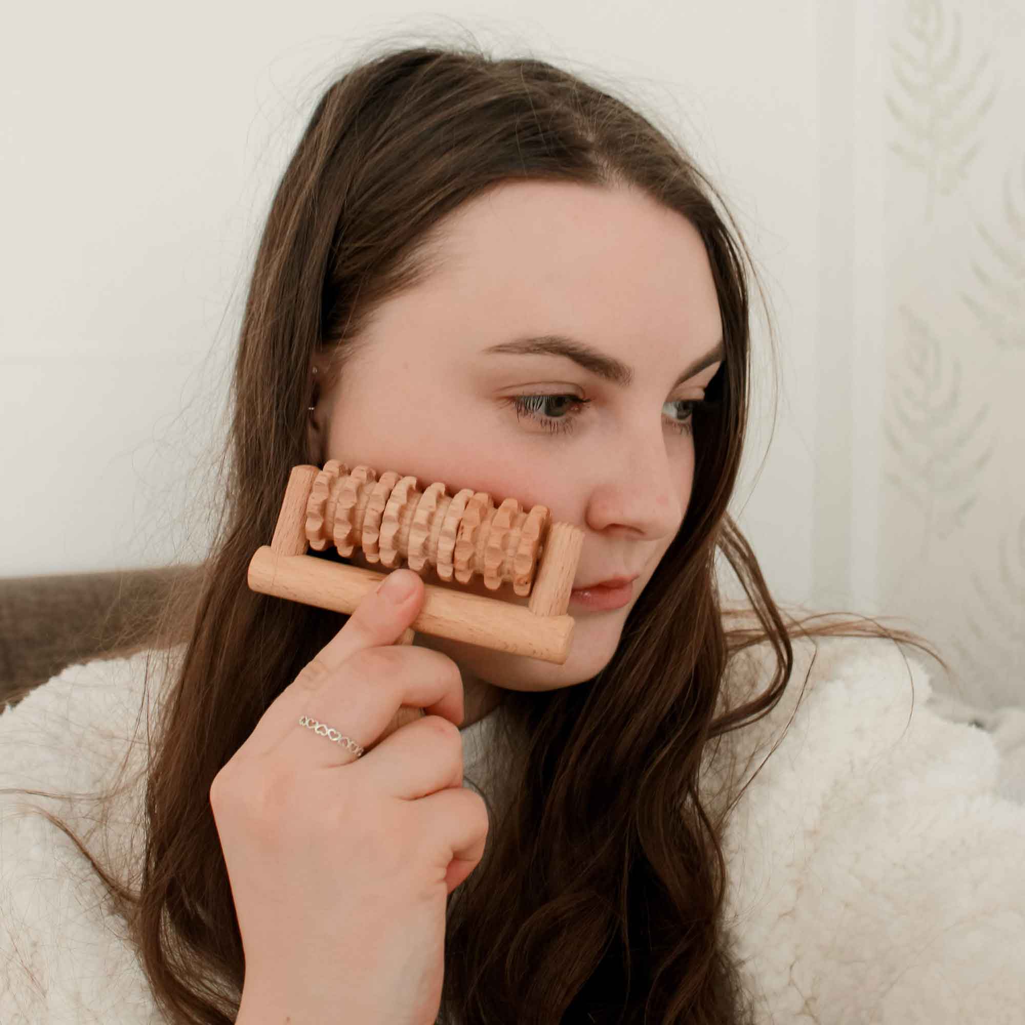 Wooden face massager used gently on the cheek as part of a face-care routine
