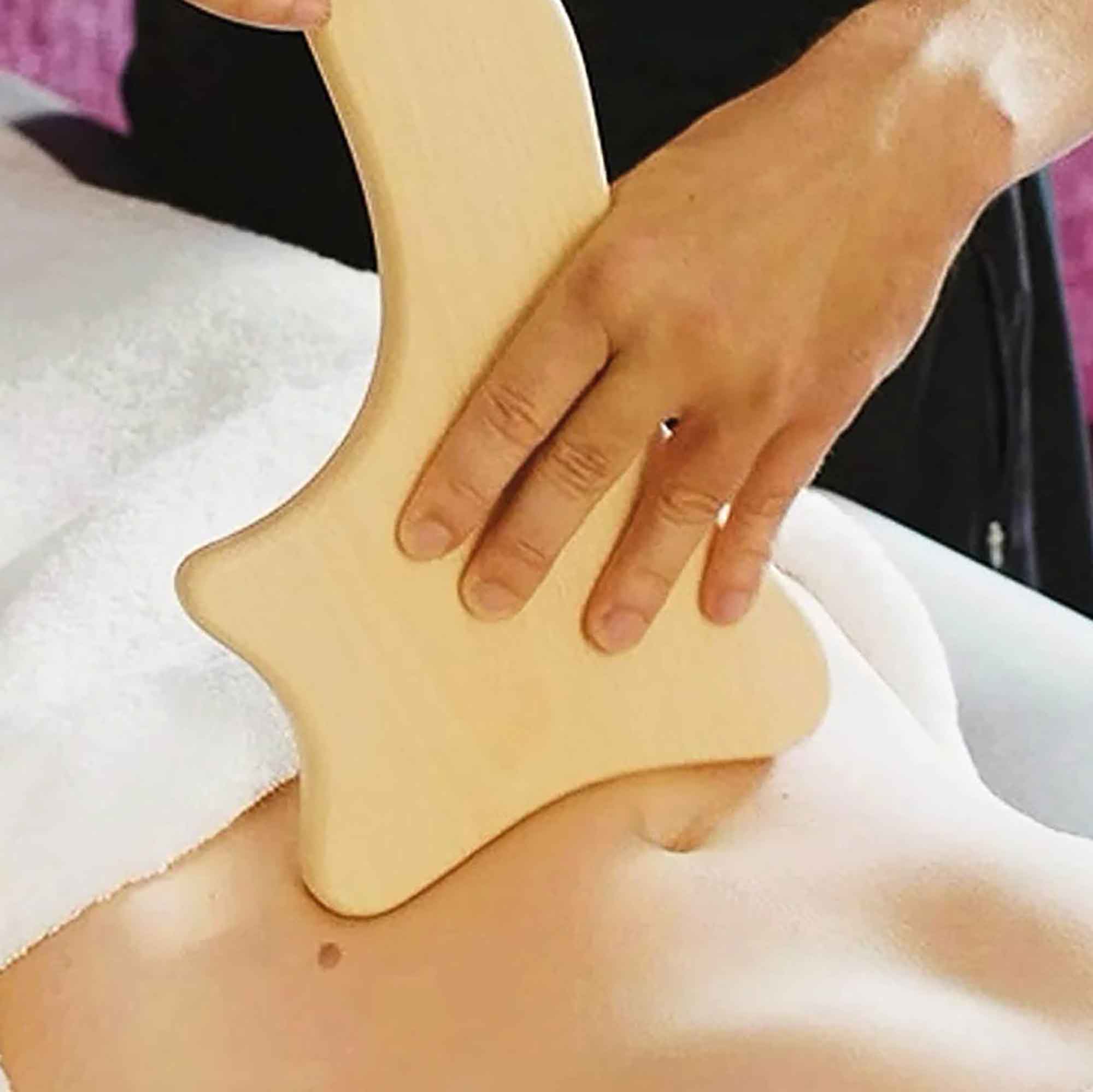 Wooden gua sha style tool used gently as part of a self-care routine
