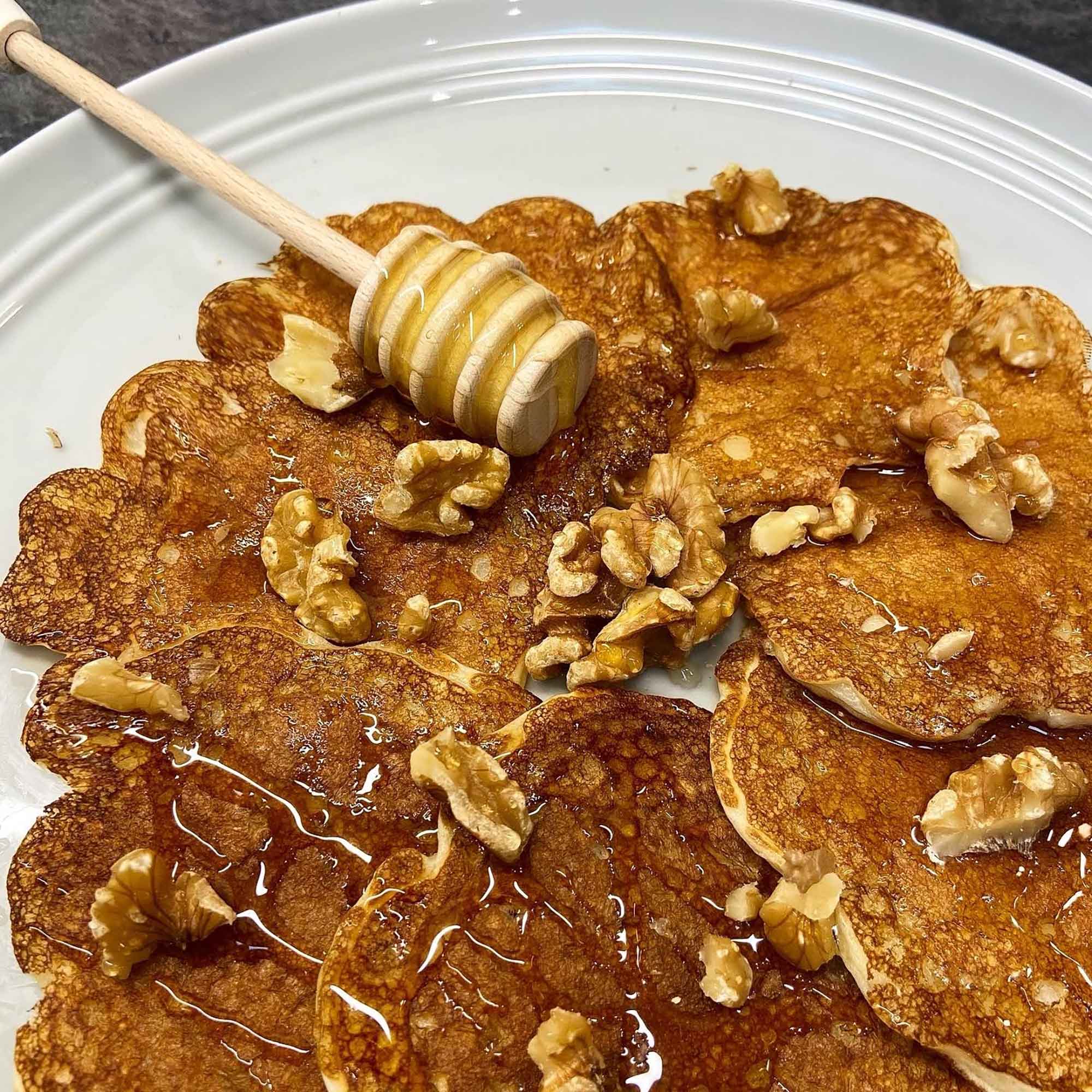 Wooden honey dipper with honey over pancakes for everyday kitchen use