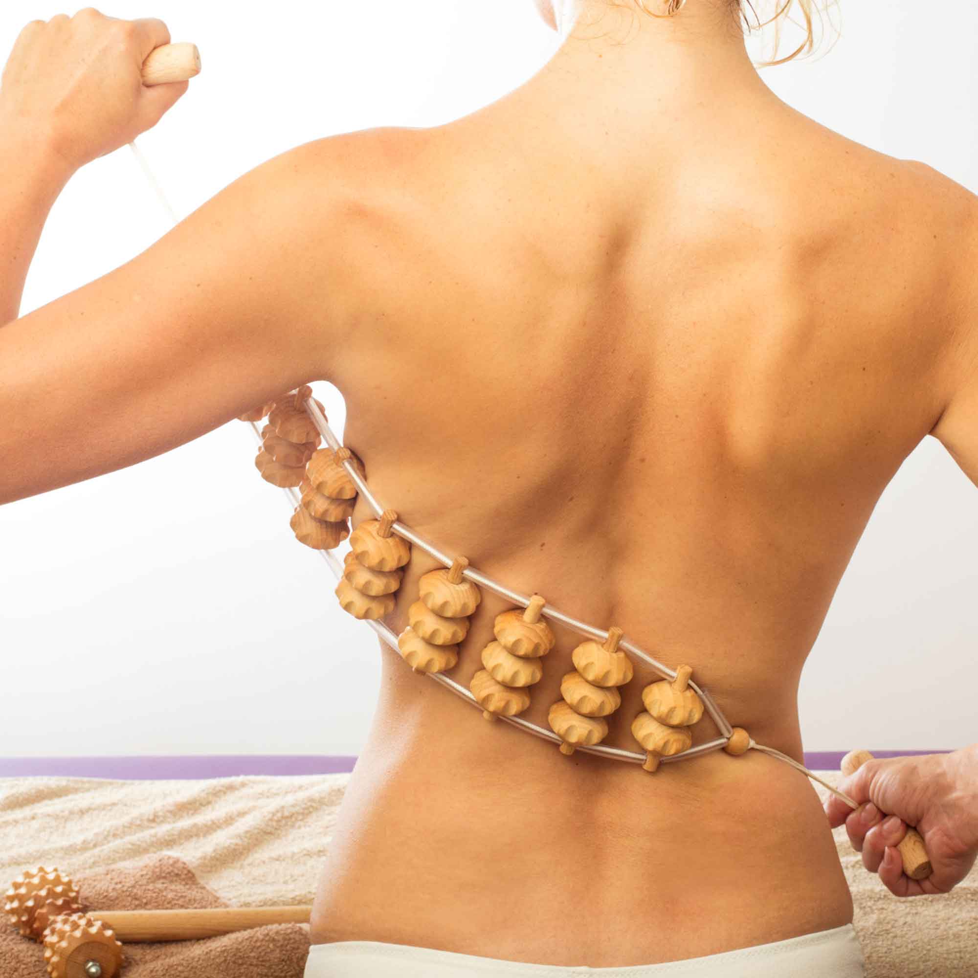 Wooden massage roller used gently on the back as part of a self-care routine