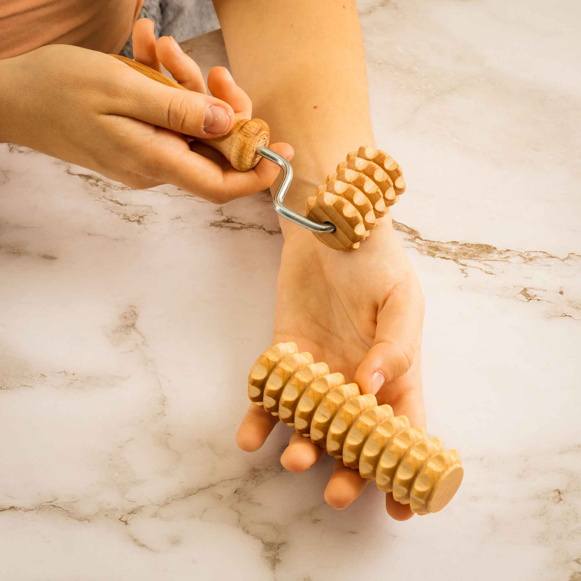 Wooden massage roller used gently on the arm as part of a self-care routine
