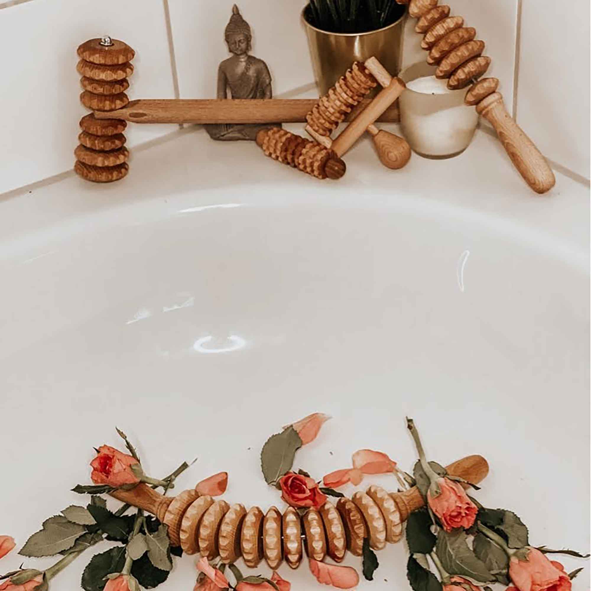 Wooden massage tools arranged beside a bathtub for a calm self-care routine