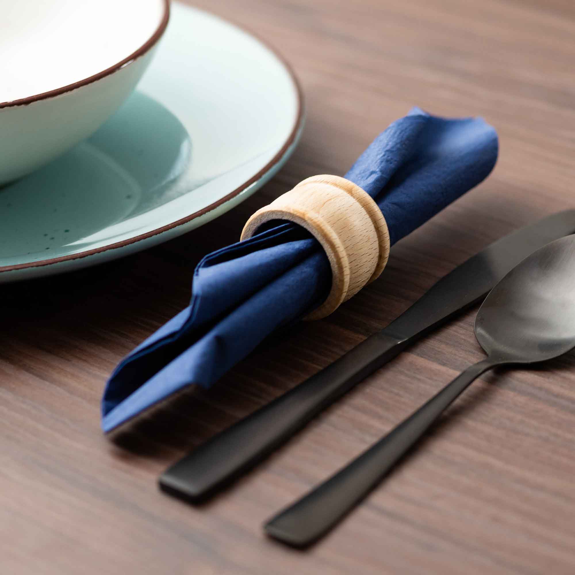 Wooden napkin ring holding a blue napkin for table decoration