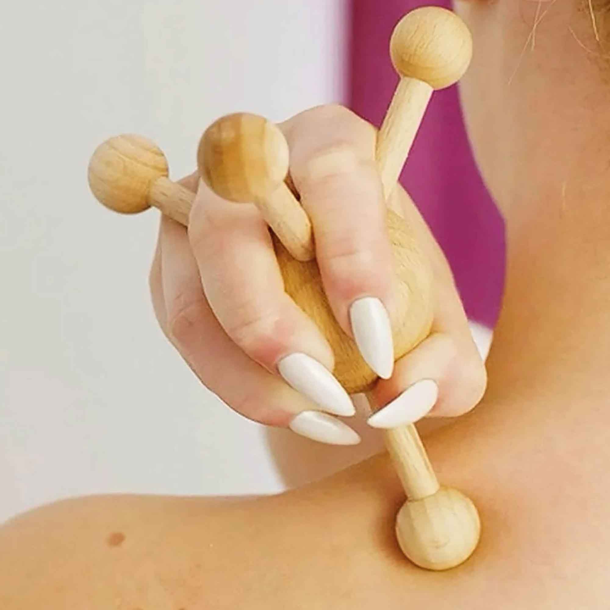 Wooden massage tool used gently on the shoulder as part of a self-care routine