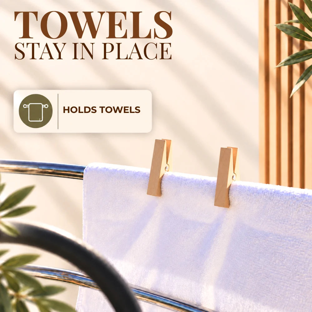 A white towel clipped to a metal bar with two wooden clothespins, with promotional text reading 'TOWELS STAY IN PLACE' and 'HOLDS TOWELS'.