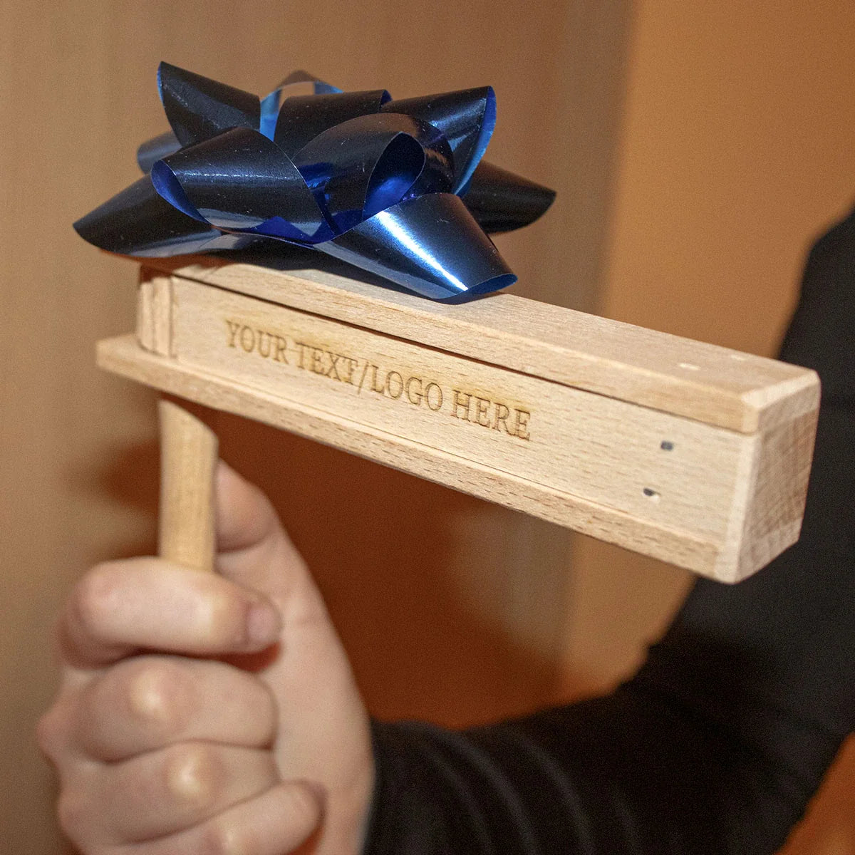 Personne tenant une cliquet en bois personnalisée lors d'un événement sportif, démontrant son utilisation pratique et son son vibrant