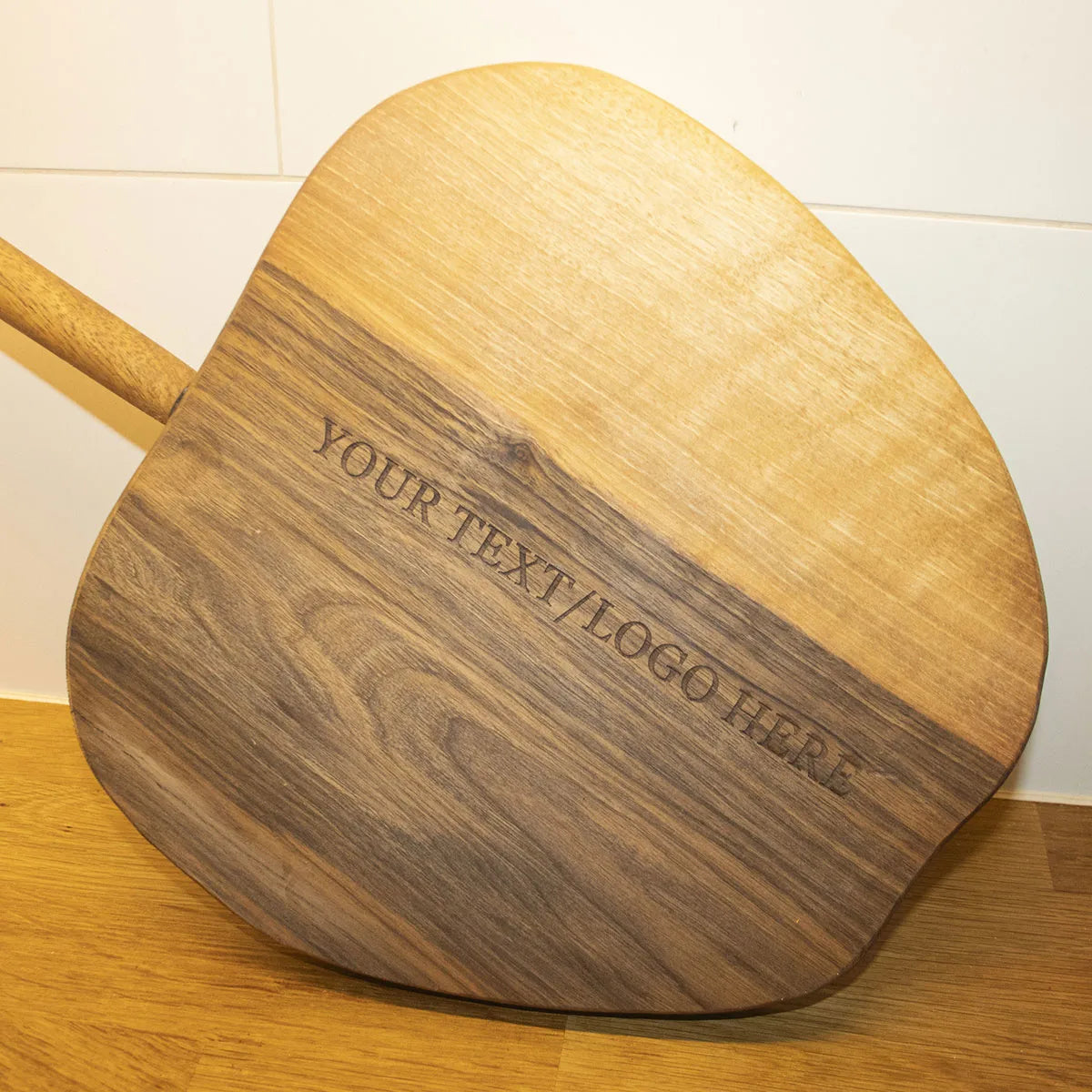 Zijaanzicht dat de dikte en vakmanschap van het appelvormige walnoten snijplankje toont