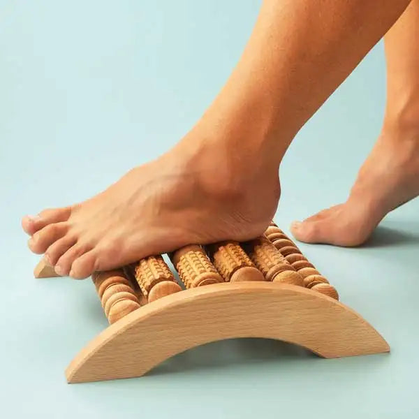 Wooden foot roller massage board with curved design and small cylindrical rollers for relaxation.