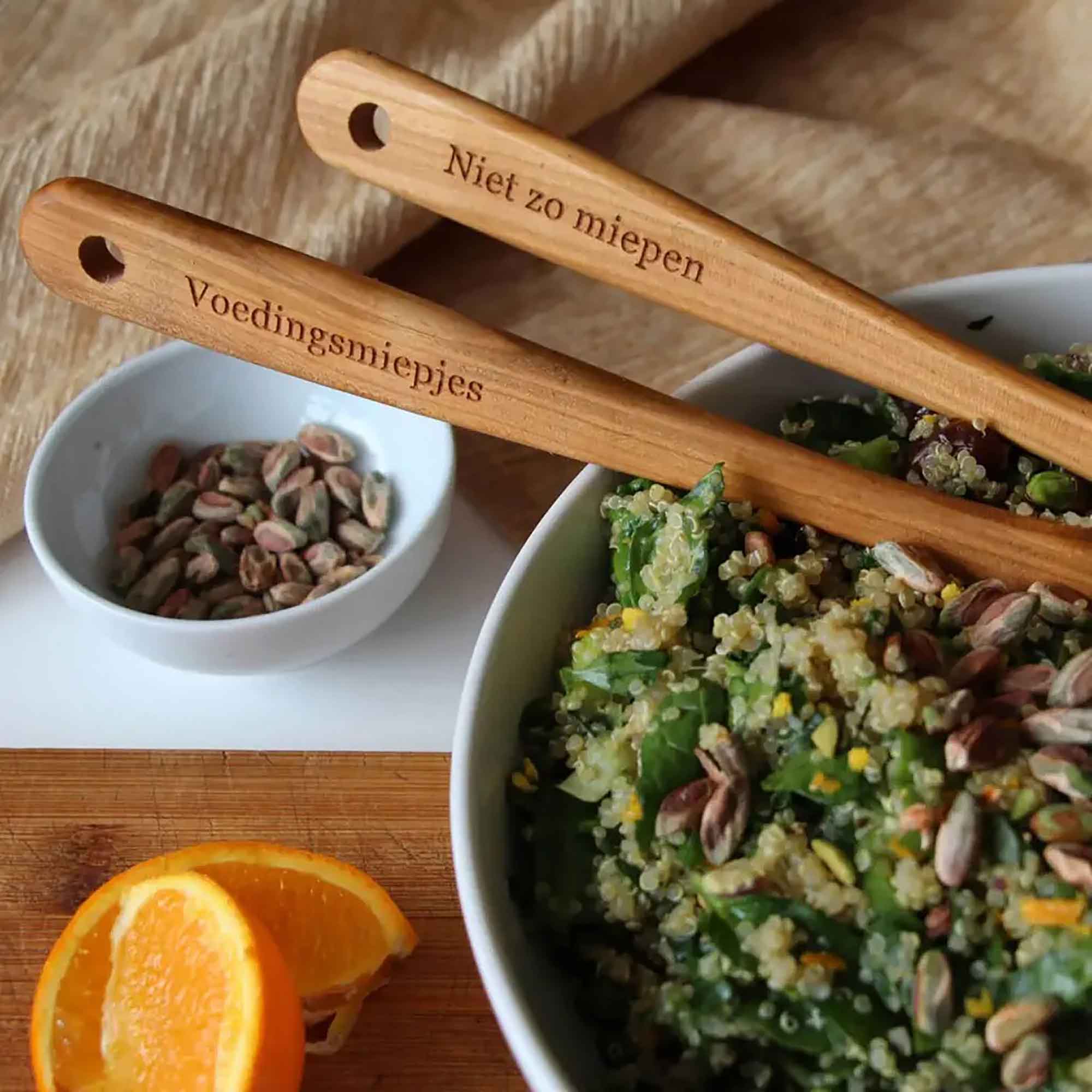 Personalized wooden spoons with engraved text shown beside a salad bowl