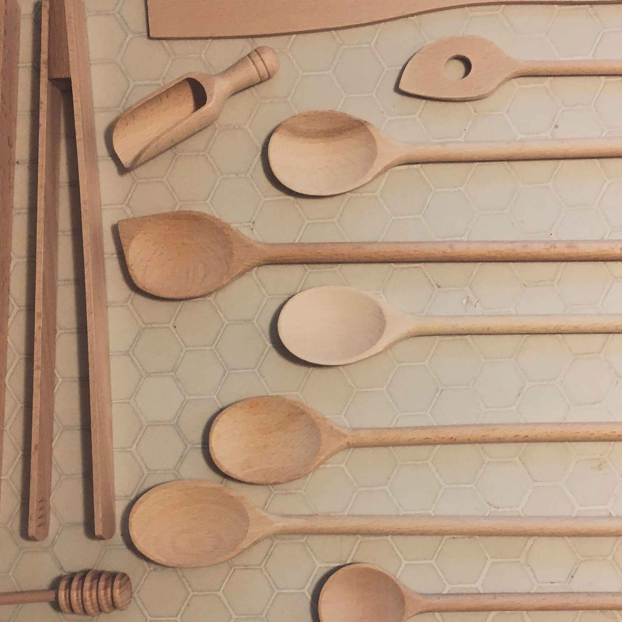 Wooden kitchen utensils and honey dipper arranged on a tiled kitchen surface
