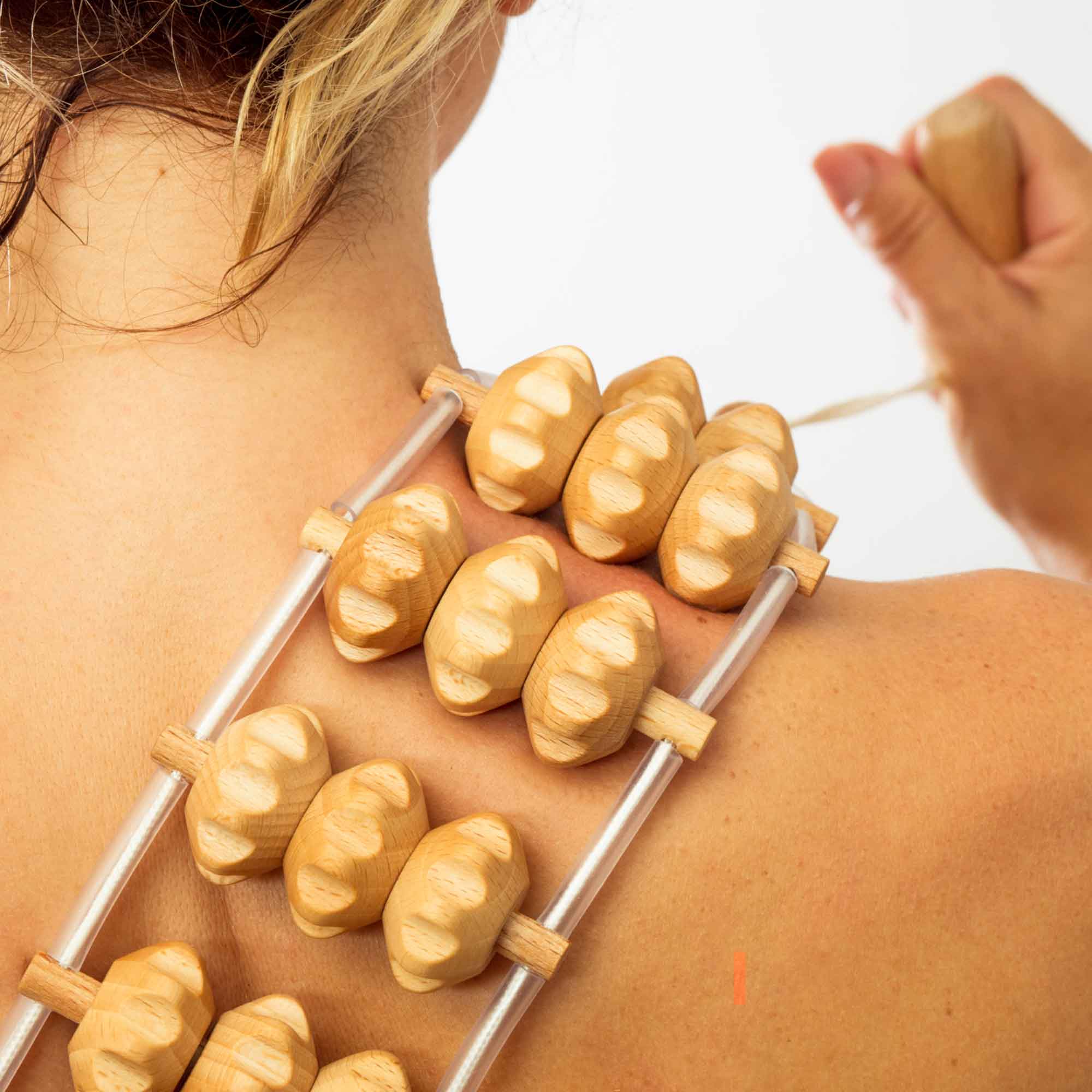Wooden massage roller used gently on the upper back as part of a self-care routine