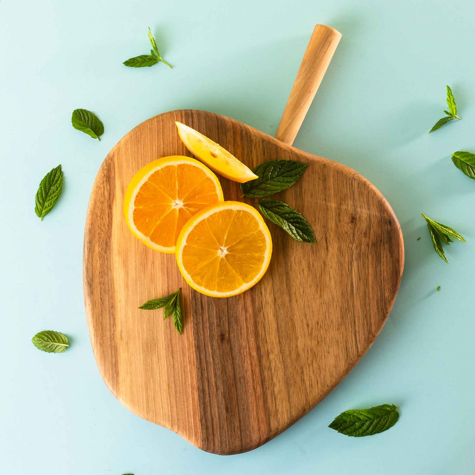 Wooden serving board with citrus shown as a practical home gift idea