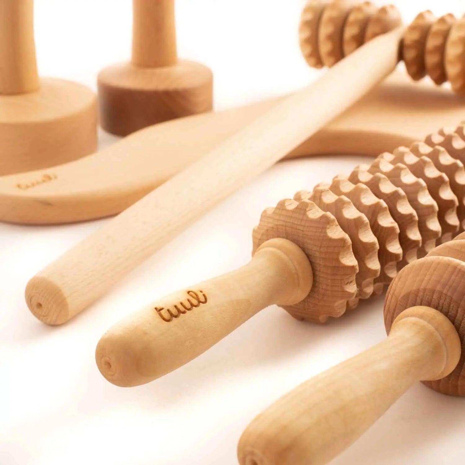 Assorted maderotherapy tools in beechwood—cups, rollers, paddle and multi-piece sets—on a neutral background, Tuuli collection