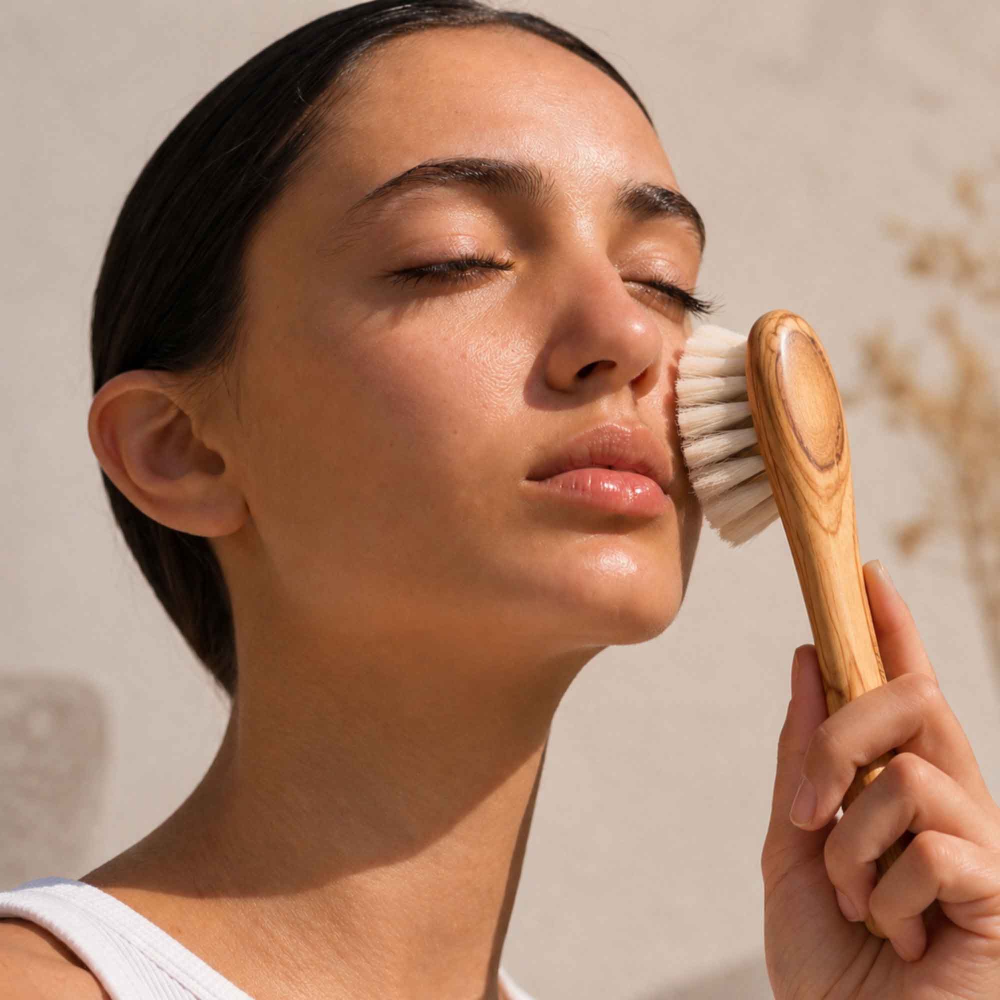 Mulher a usar uma escova de massagem facial em madeira de oliveira na bochecha