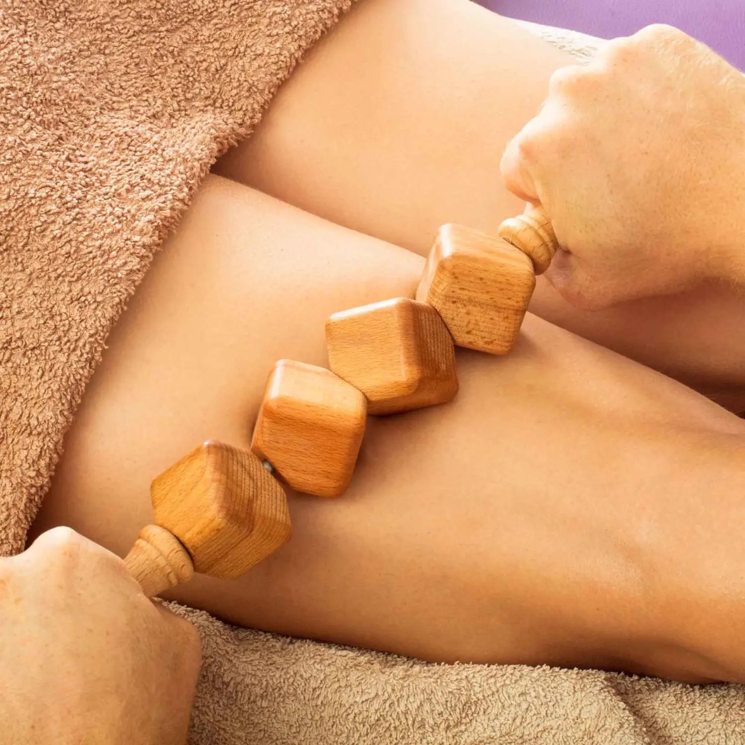 Rodillo de masaje con dados de madera de haya de 40 cm con mango de fácil agarre sobre fondo neutro