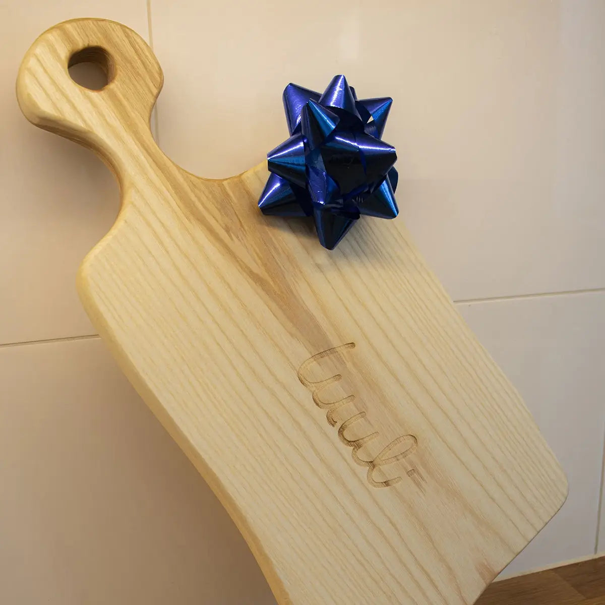 Custom engraved ash wood cutting board displayed in modern kitchen setting