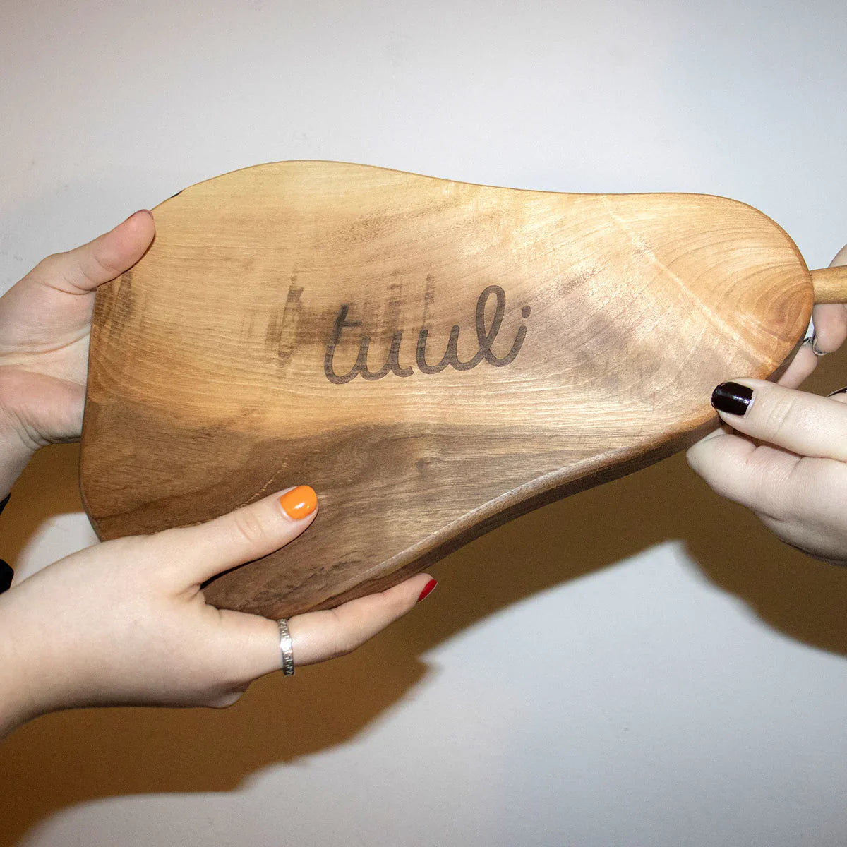 Detail of custom laser engraving process on pear-shaped walnut cutting board
